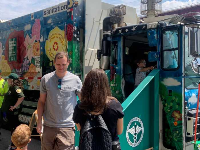 sanitation truck during the day with people standing next to it
