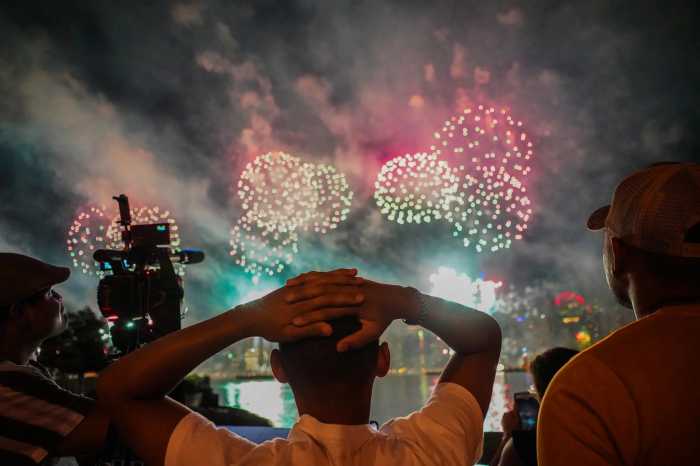 Person holding hands on head while watching July 4 fireworks amid smoky haze